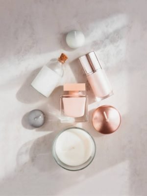 Spa beauty products flatlay in shape of Christmas tree on white marble table. Coconut oil, luxury cream, serum, perfume, candles.